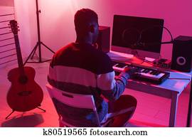 Professional african american musician recording synthesizer in digital studio at home, Music production technology concept.