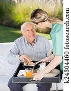 Female Caretaker Serving Breakfast To Senior Man Female Caretaker Serving Breakfast To Senior Man