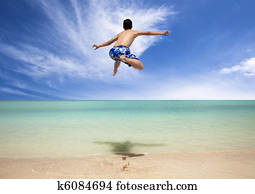 Happy young man jumping on the beach