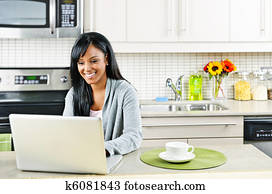 Woman using computer in kitchen