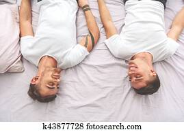 Young gays luxuriating on bedding
