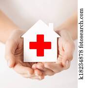 hands holding paper house with red cross hands holding paper house with red cross