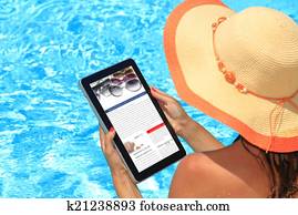 Woman holding tablet computer in the pool