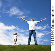 young man relax on the green field with his dog 