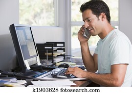 homem, em, escritório lar, ligado, telefone, usando computador, e, sorrindo