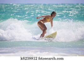 girl in a yellow bikini surfing in Hawaii girl in a yellow bikini surfing in Hawaii