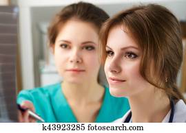 Two female medicine doctors looking at patient lungs x-ray image