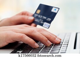 Hand typing on laptop with credit card.