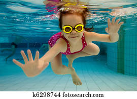 The girl smiles, swimming under water in the pool