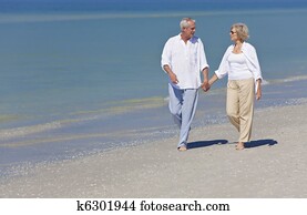 Happy Senior Couple Walking Holding Hands on Beach
