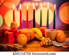 Kwanzaa festive concept with seven candles red, black and green, gift box, pumpkin, bowl and fruit on light blur bokeh background Kwanzaa festive concept with seven candles red, black and green, gift box, pumpkin, bowl and fruit on light blur bokeh background
