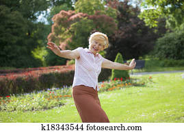 Gaiety. Delighted Playful Mature Woman with Outstretched Arms Laughing Outside