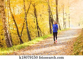 Active and sporty woman runner in autumn nature