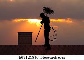 chimney sweep on roof at sunset chimney sweep on roof at sunset