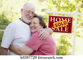 Senior Couple in Front of Sold Real Estate Sign