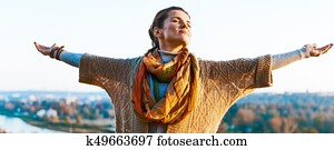 Happy young woman in autumn outdoors in evening rejoicing