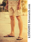 Man Feet wearing shorts and flip flops standing Outdoor summer vacations lifestyle concept