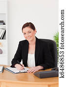 Beautiful red-haired woman in suit writing on a notepad 