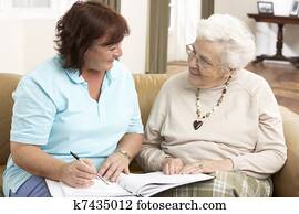 Senior Woman In Discussion With Health Visitor At Home