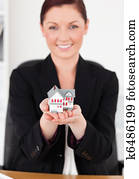 Young attractive red-haired woman in suit holding a miniature 