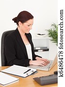 Young beautiful red-haired woman in suit typing on her laptop