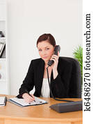 Young gorgeous red-haired woman in suit writing on a notepad