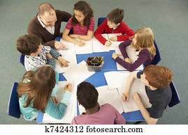 Overhead View Of Schoolchildren Working Together At Desk With Teacher