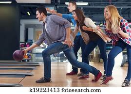 Friends cheering their friend while throwing bowling ball Friends cheering their friend while throwing bowling ball
