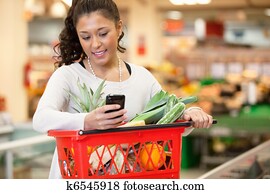 Smiling woman using mobile phone in shopping store
