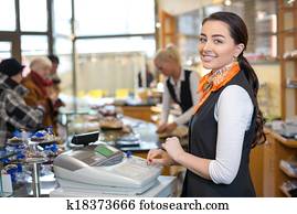 Shopkeeper and saleswoman at cash register or cash desk Shopkeeper and saleswoman at cash register or cash desk