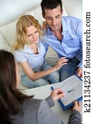 Cheerful couple signing property contract with real-estate agent