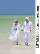 Happy Senior Couple Walking Holding Hands on a Tropical Beach Happy Senior Couple Walking Holding Hands on a Tropical Beach