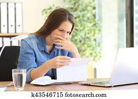 Worried entrepreneur girl reading a letter Worried entrepreneur girl reading a letter