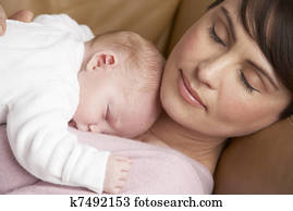 Portrait Of Mother Resting With Newborn Baby At Home