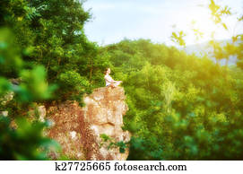 woman meditating in lotus posture, doing yoga on top of the mountain 