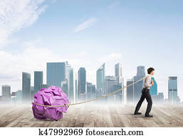 Man pulling with effort big crumpled ball of paper as creativity sign