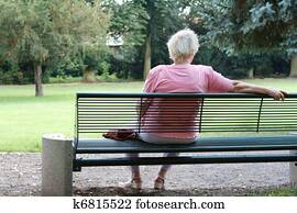 Senior woman is sitting alone in a park