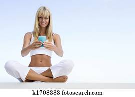 Woman sitting and meditating outdoors while holding a candle