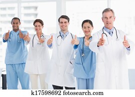 Confident doctors gesturing thumbs up at hospital