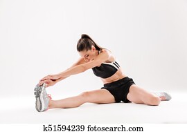 Full length portrait of a healthy motivated sportwoman stretching muscles