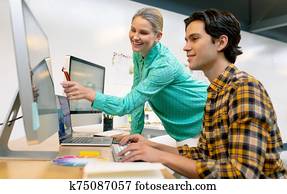 Male and female graphic designer discussing over computer at desk Male and female graphic designer discussing over computer at desk