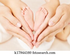 Newborn baby feet in parents hands. Love simbol as heart sign Newborn baby feet in parents hands. Love simbol as heart sign