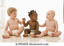 Three babies sitting indoors holding hands
