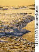 Waves lapping beach at sunset.
