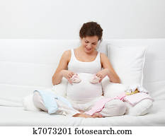 Beautiful pregnant woman choosing baby's clothes