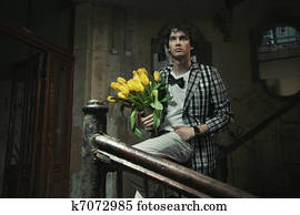 Young fashionable man holding bunch of flowers