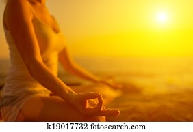 hand of  woman meditating in a yoga pose on beach at sunset