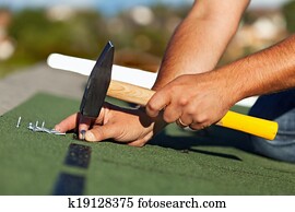Man hands fastening bitumen roof shingles Man hands fastening bitumen roof shingles