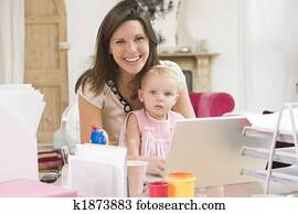 Mother and baby in home office with laptop