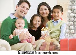 Family With New Born, Sitting On Sofa, Holding Christmas Gift